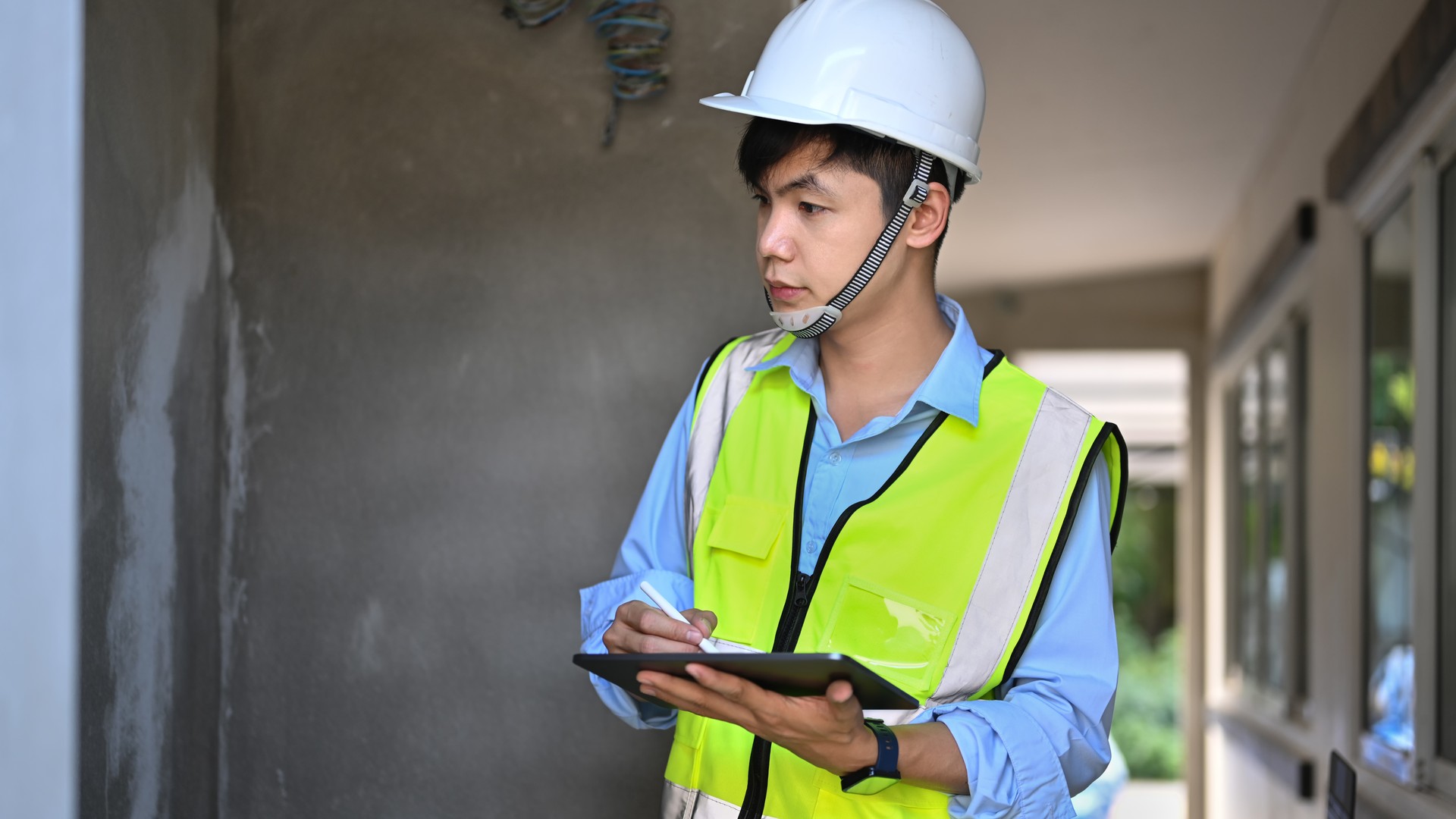 Commercial building inspector taking notes on a clipboard while checking property conditions.