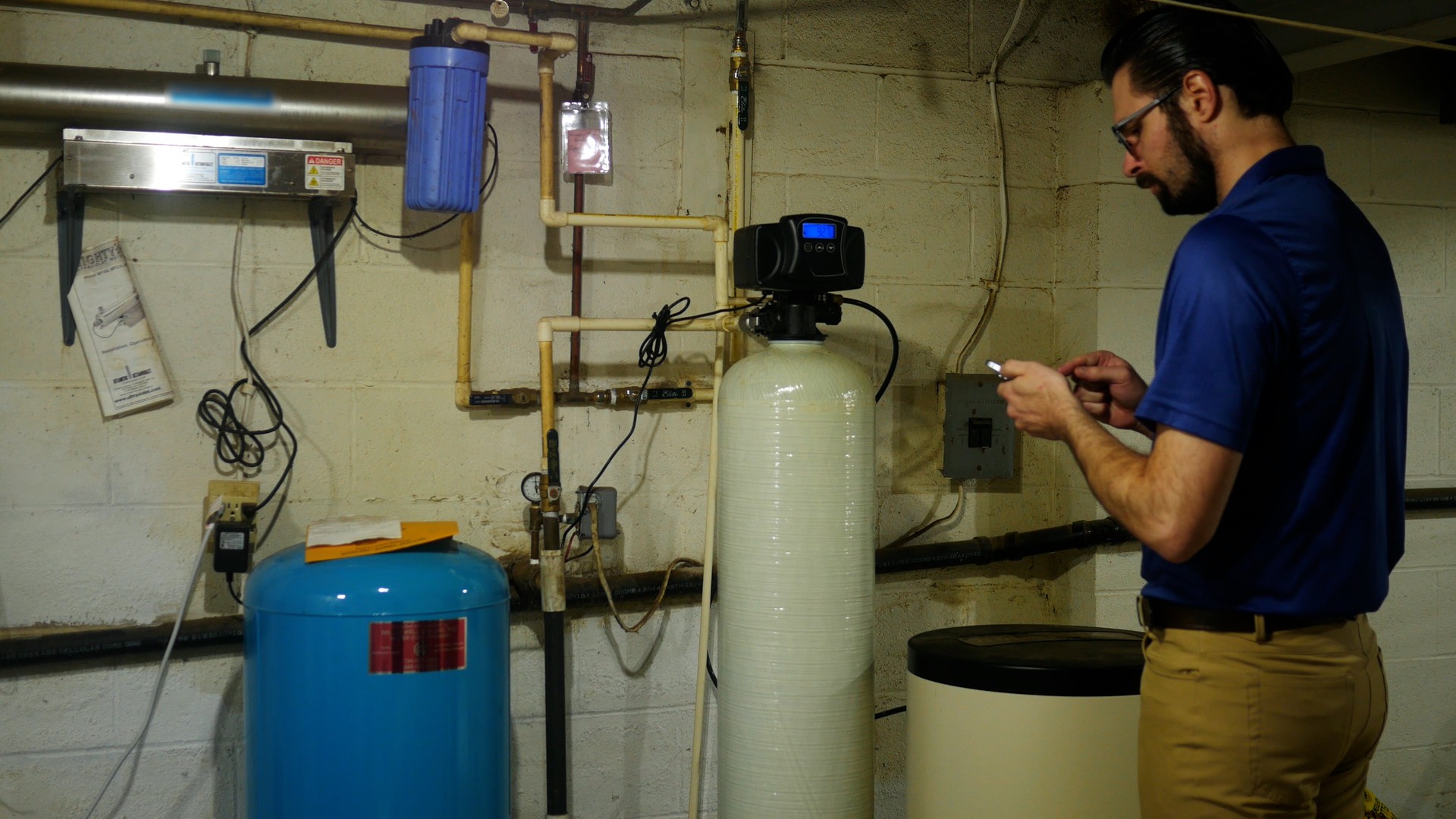 Well water specialist documenting a residential water filtration and pressure system during an inspection.