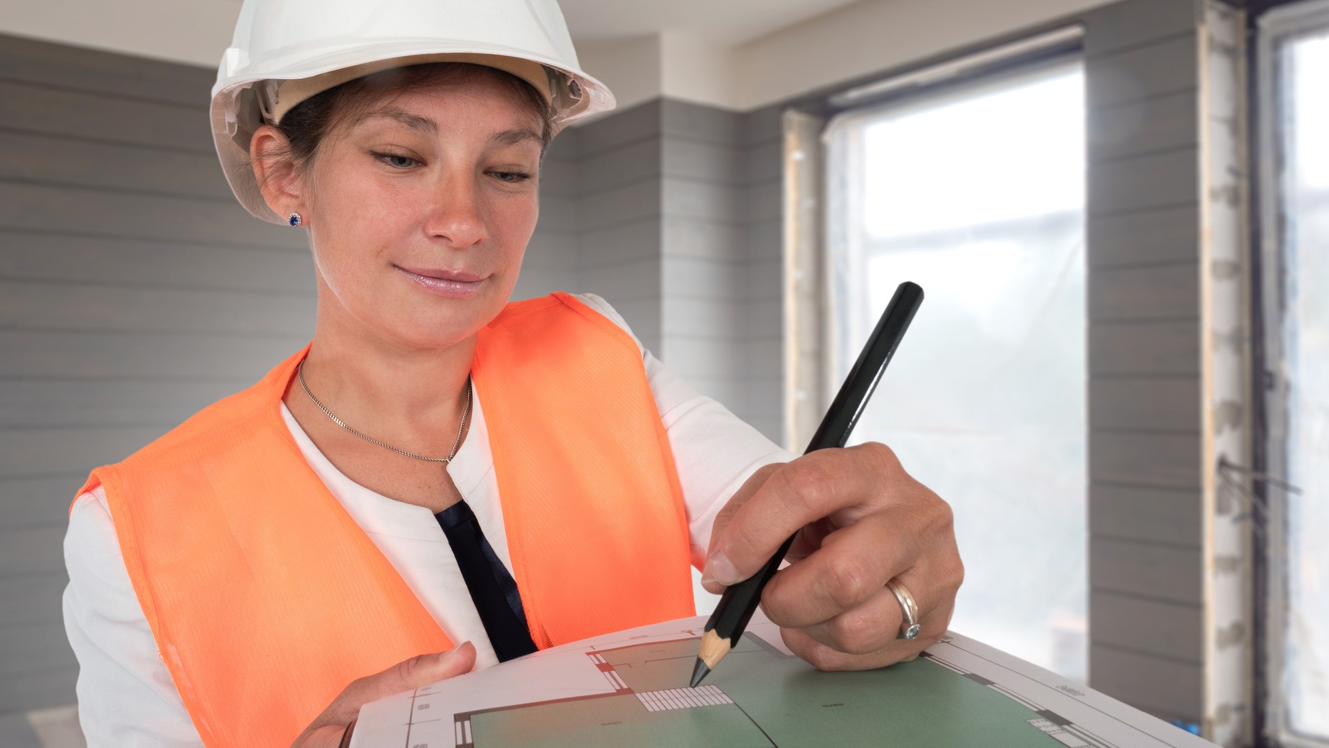 Structural engineer reviewing building plans inside an unfinished house during an inspection.