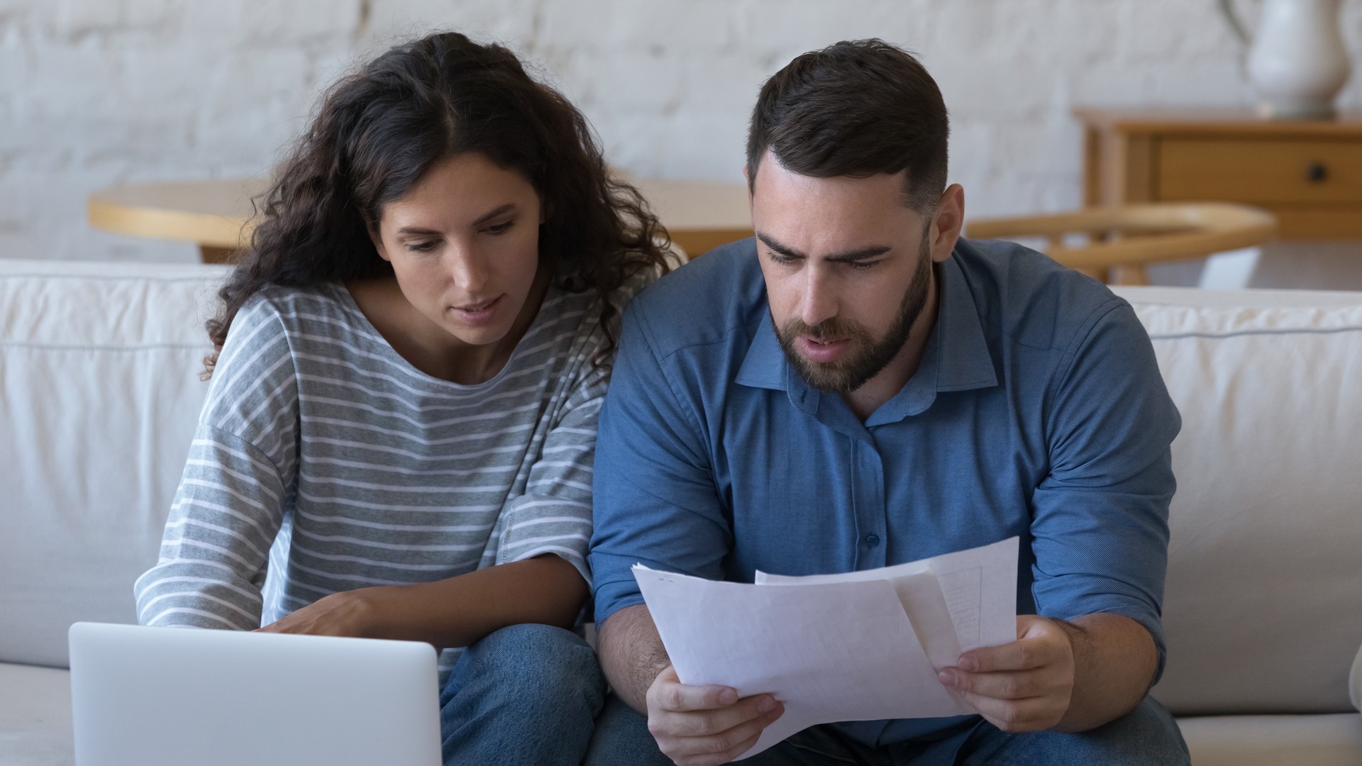 A married couple reviewing home inspection paperwork and a property purchase contract at a kitchen table, weighing whether to walk away from a Bucks County home purchase after the inspection report.