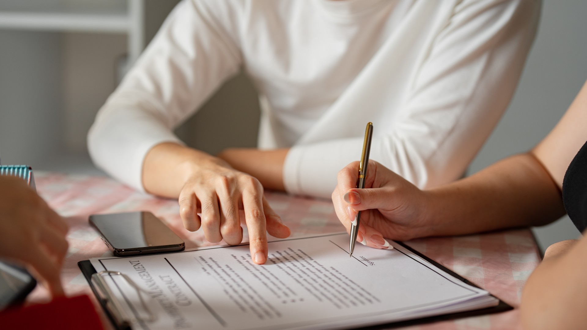 Couple reviewing a printed home inspection report and real estate paperwork at a kitchen table during a post-inspection negotiation