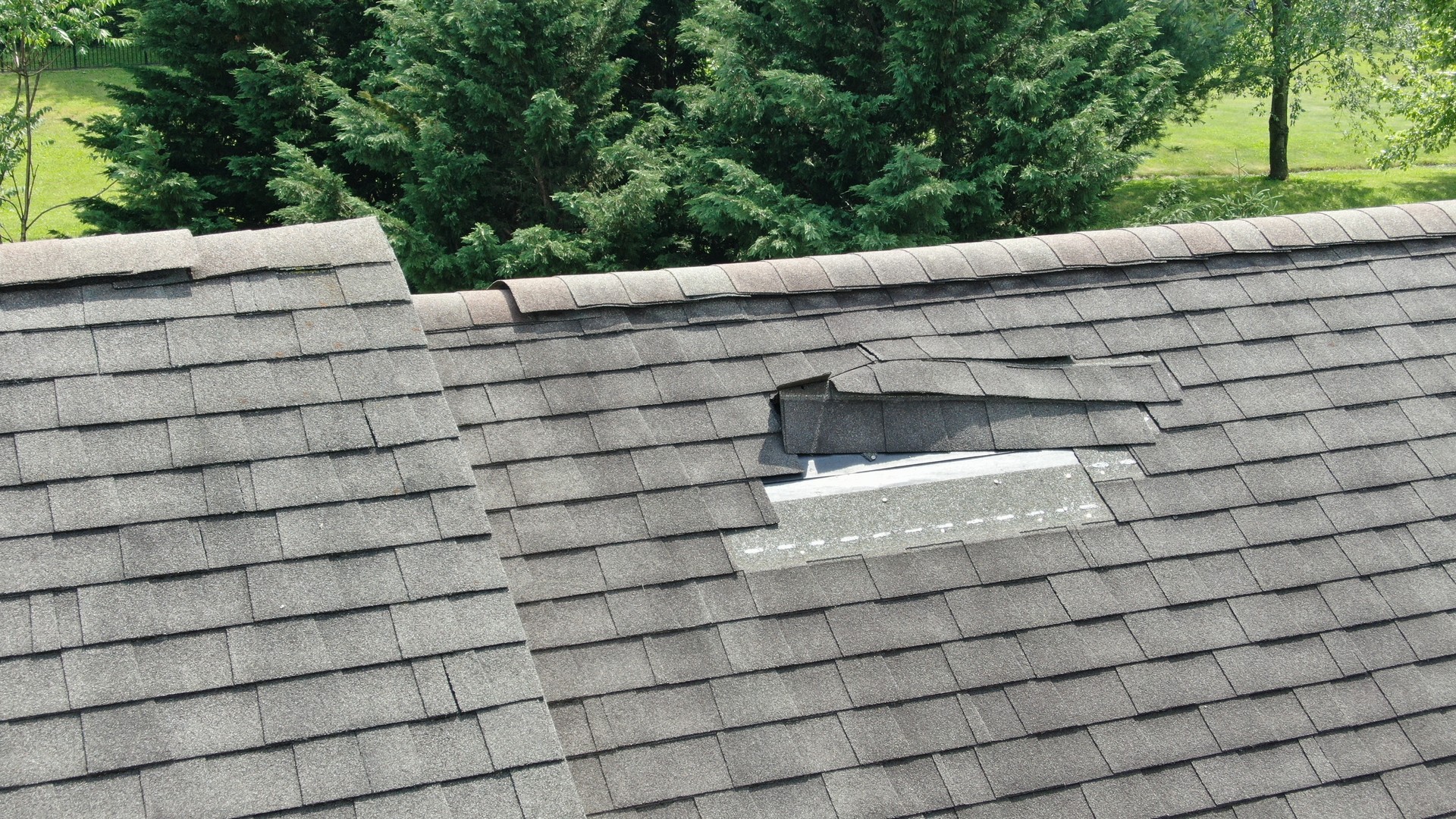 Aerial close-up of a residential roof with damaged and missing asphalt shingles found during a home inspection