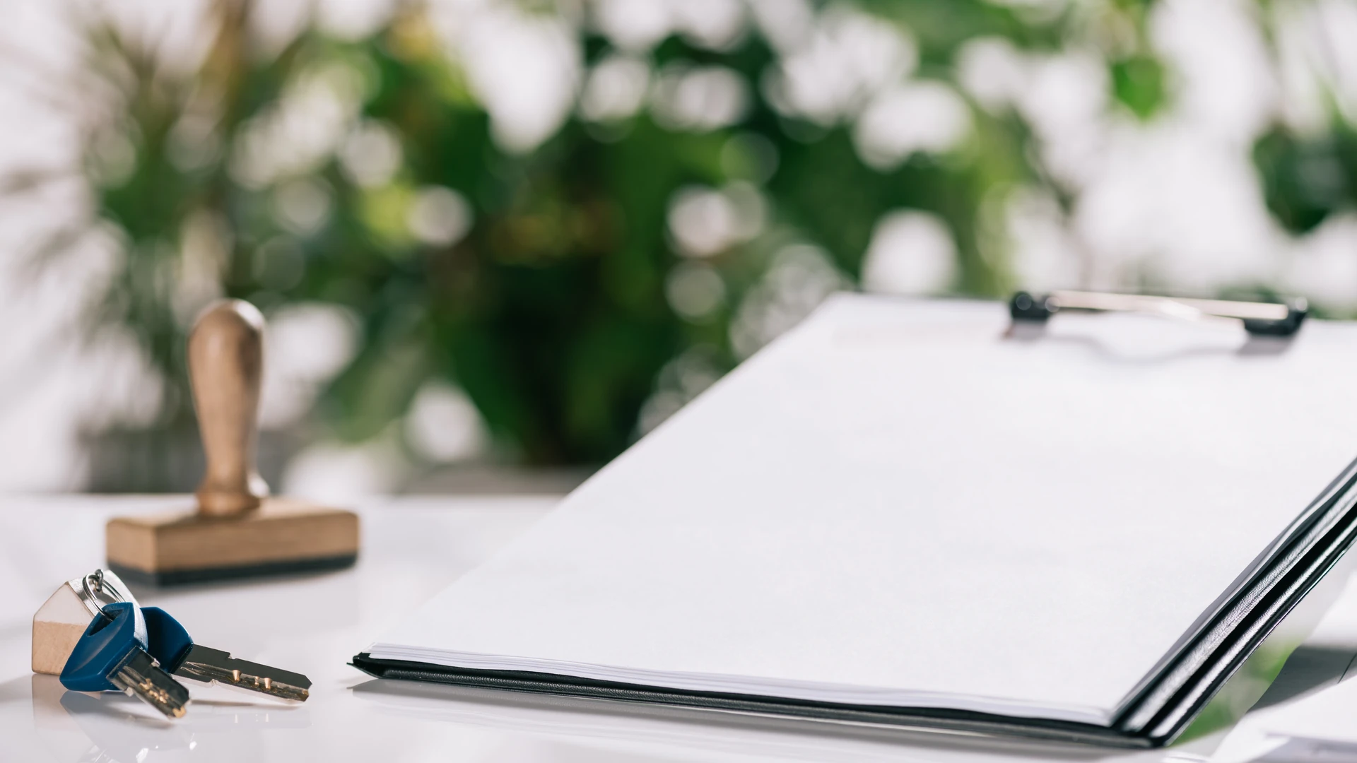 House keys, a notary stamp, and a blank report on a clipboard arranged on a closing desk