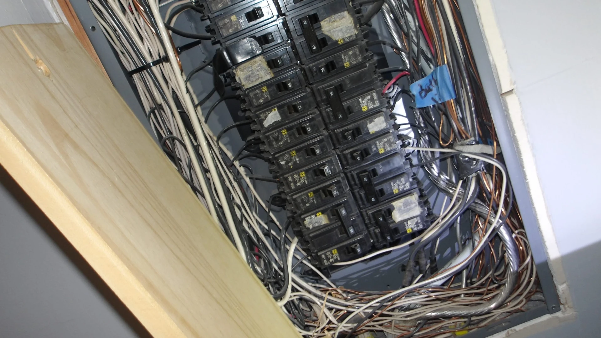 Open residential electrical panel with rows of circuit breakers and wiring, photographed during a home inspection